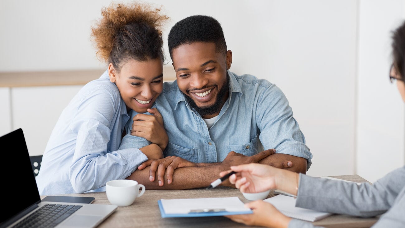 Excited couple looking over a paper being shown to them