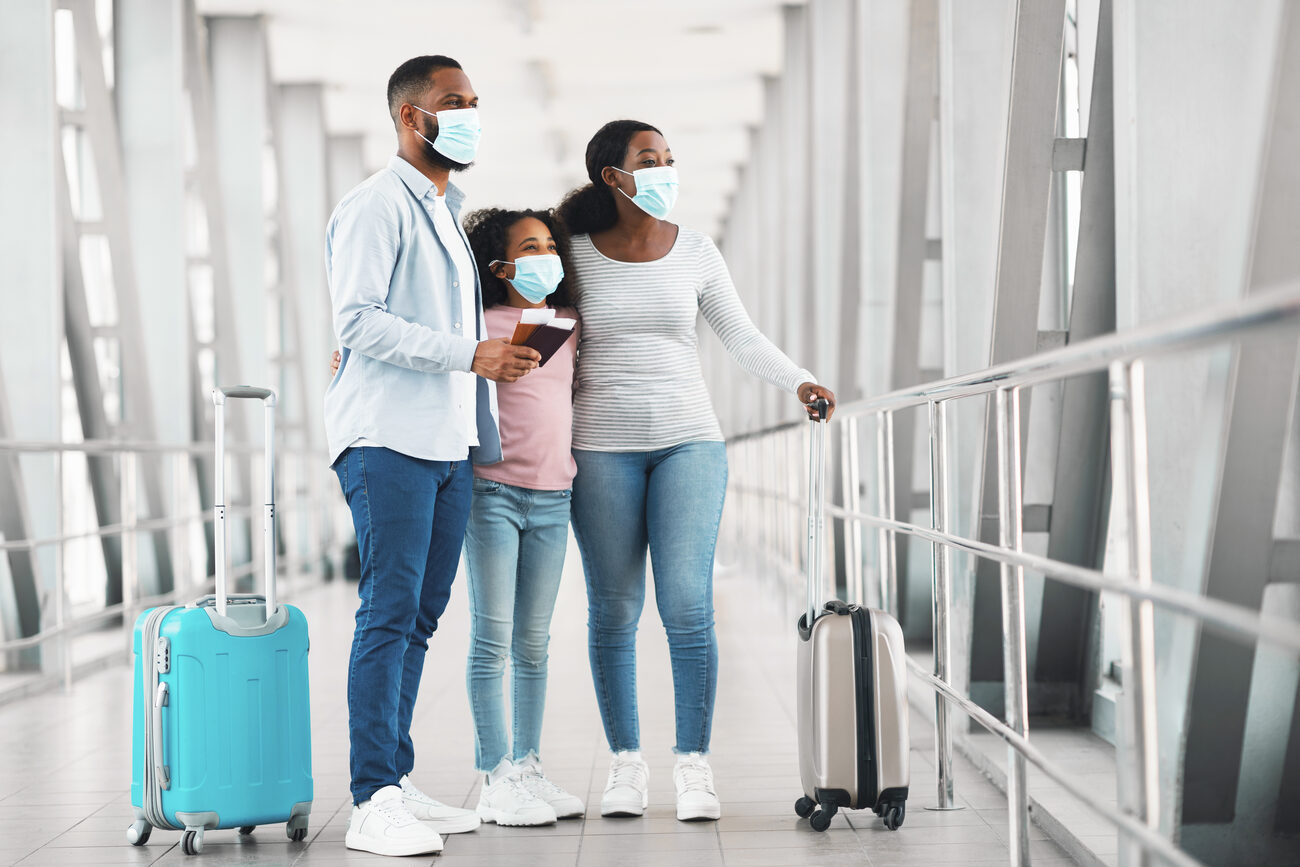 Family wearing masks with their luggage at an airport