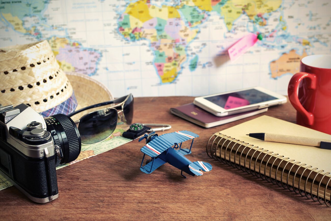 A world map in the background behind a desk with travel sundries.