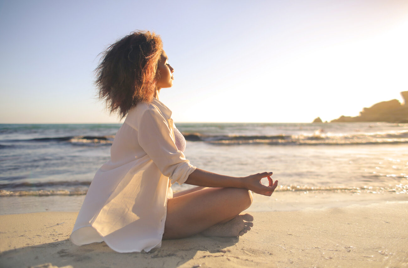 A woman practicing yoga on the beach.