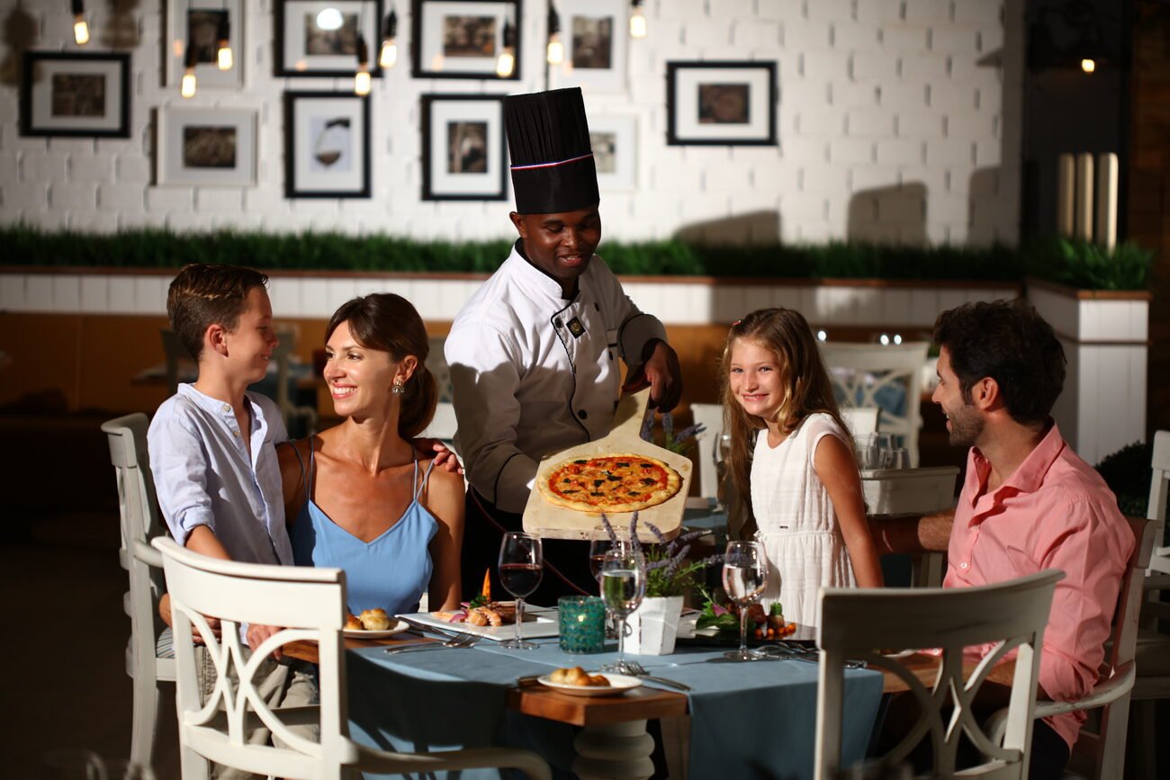 Family being served pizza at a dining table