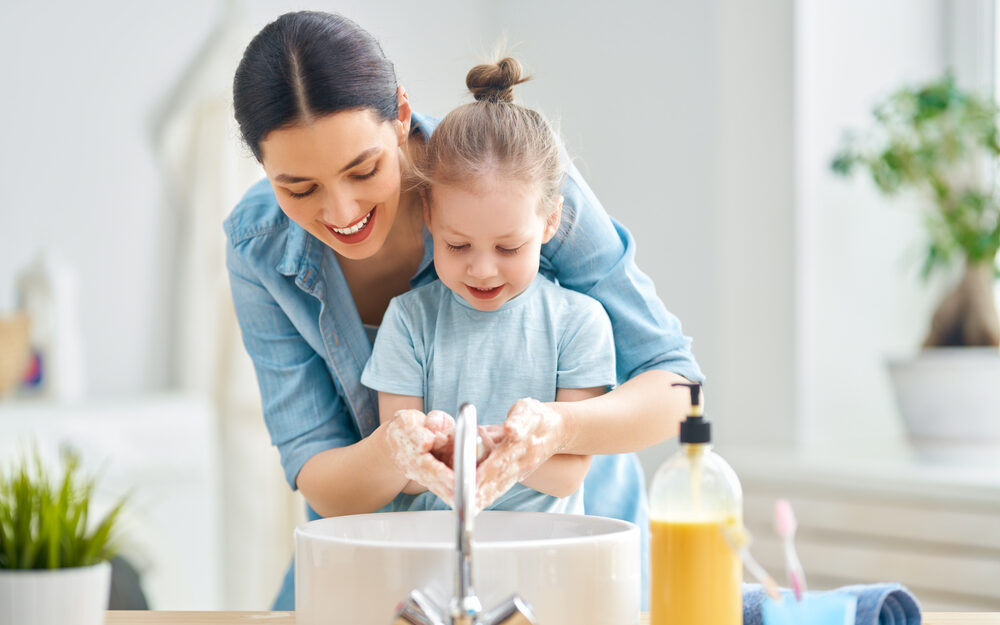 Woman helping a young child wash her hands