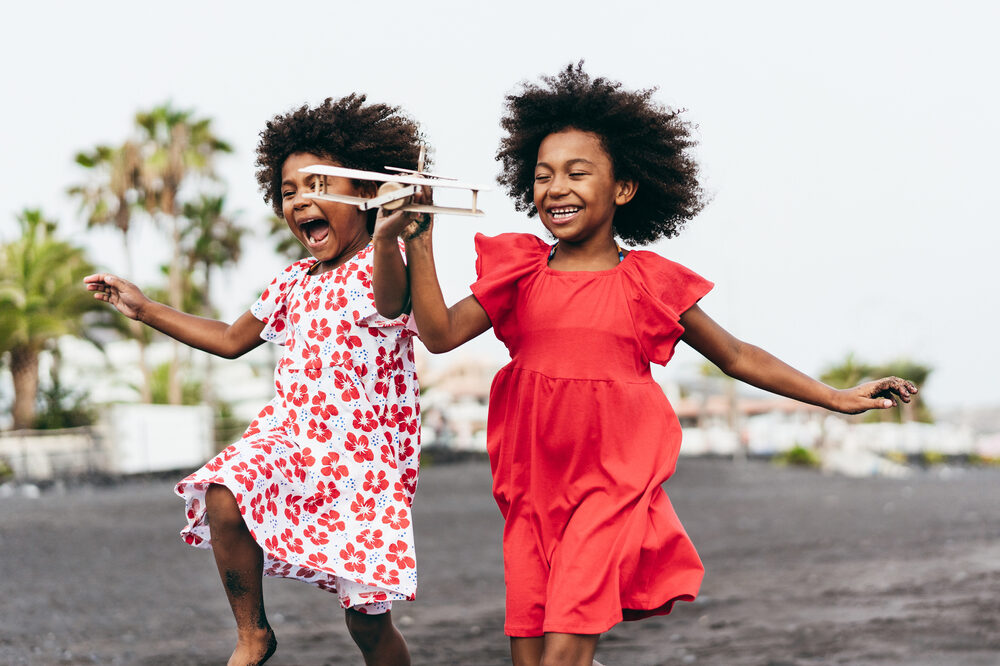 Two kids running holding a toy plane