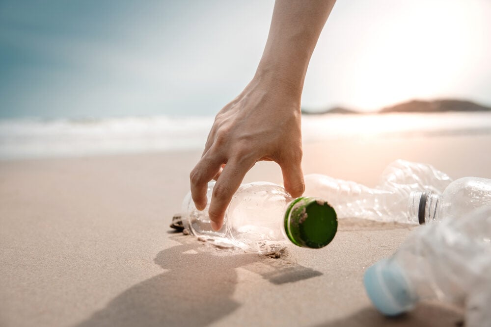 Hands grabbing empty plastic bottles on the beach