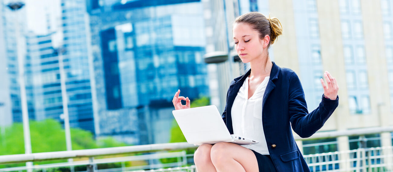 Woman meditating with a laptop in her lap