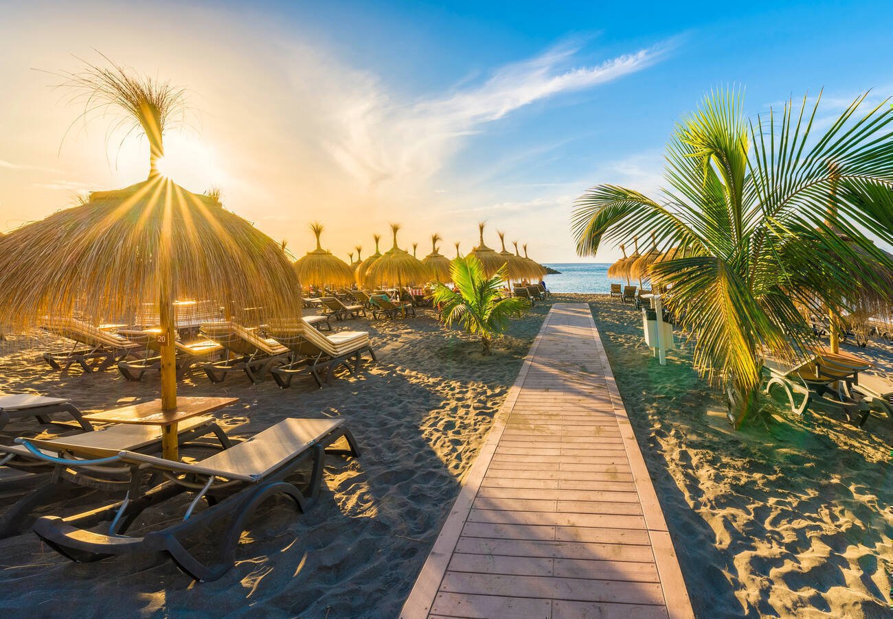 Pathway to ocean with beach chairs and straw umbrellas