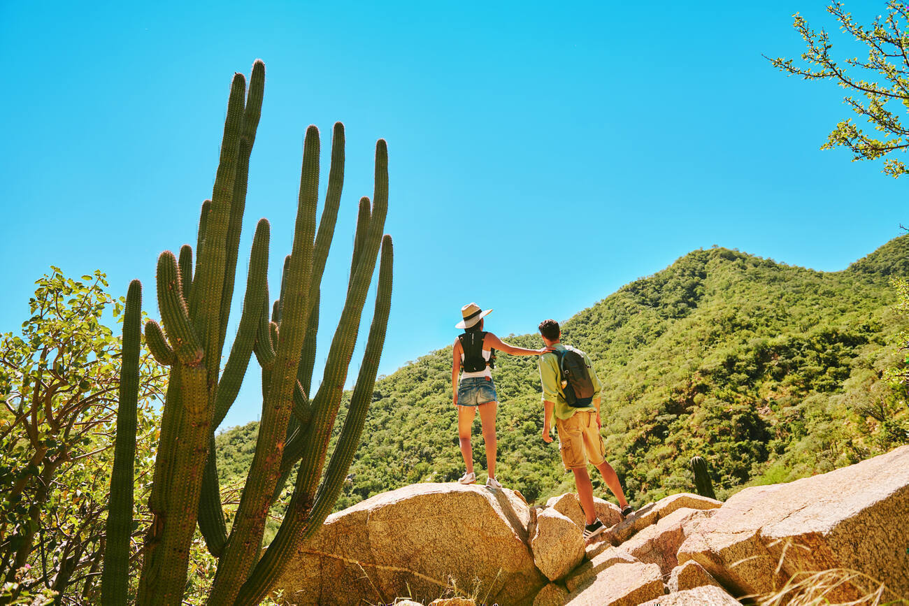 Couple peering over the edge of a hill hiking