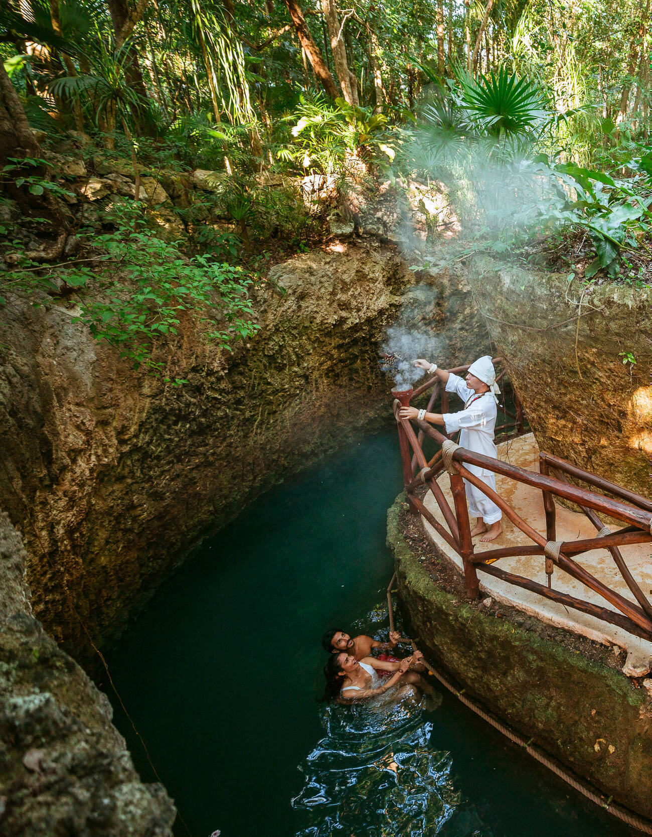 Two people in water looking up at a man