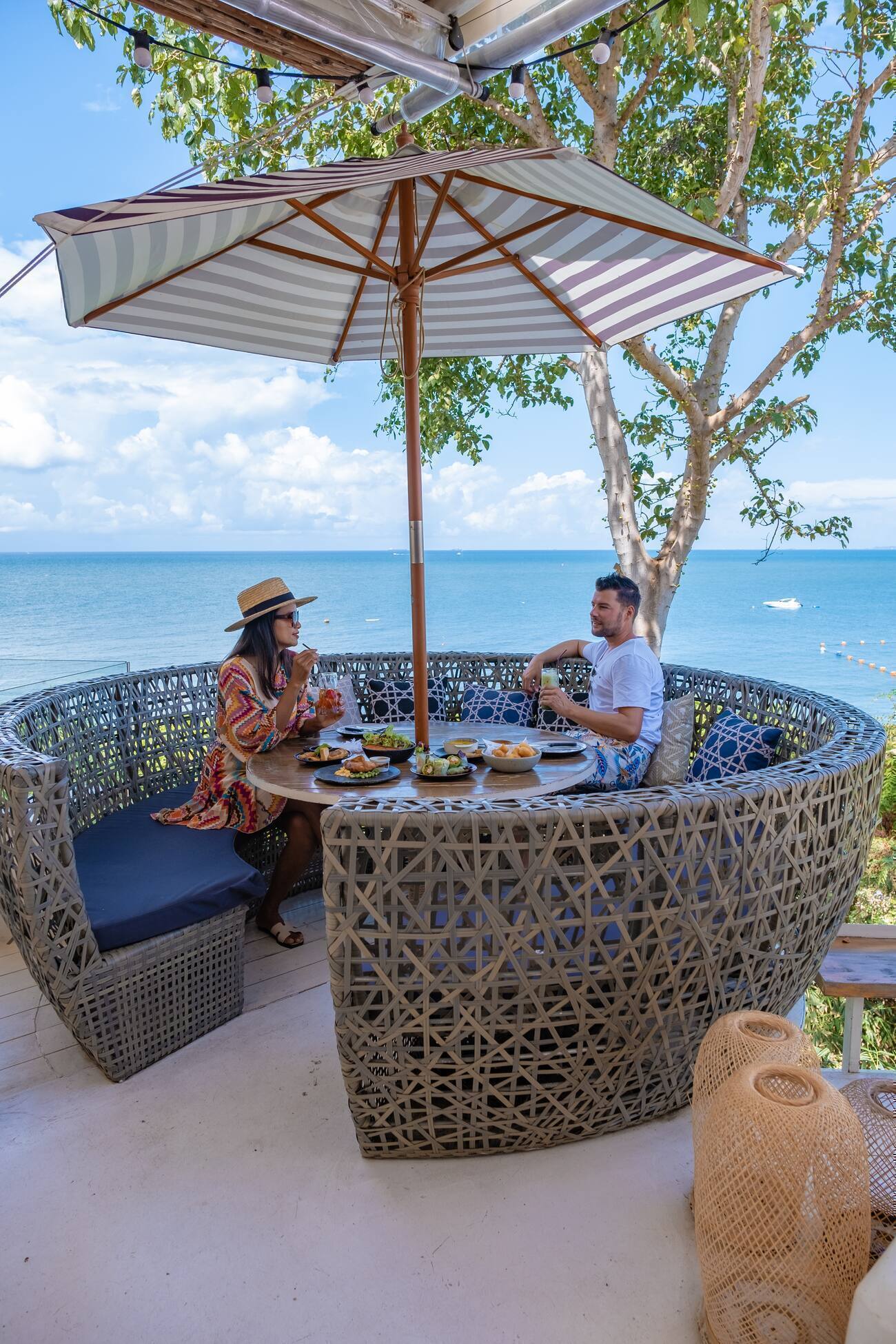 Two people eating at a table overlooking the ocean