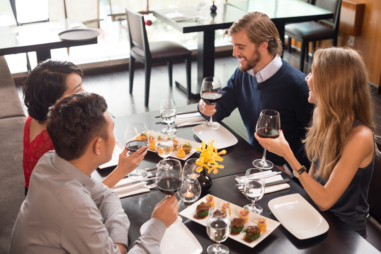 Four people eating and drinking wine