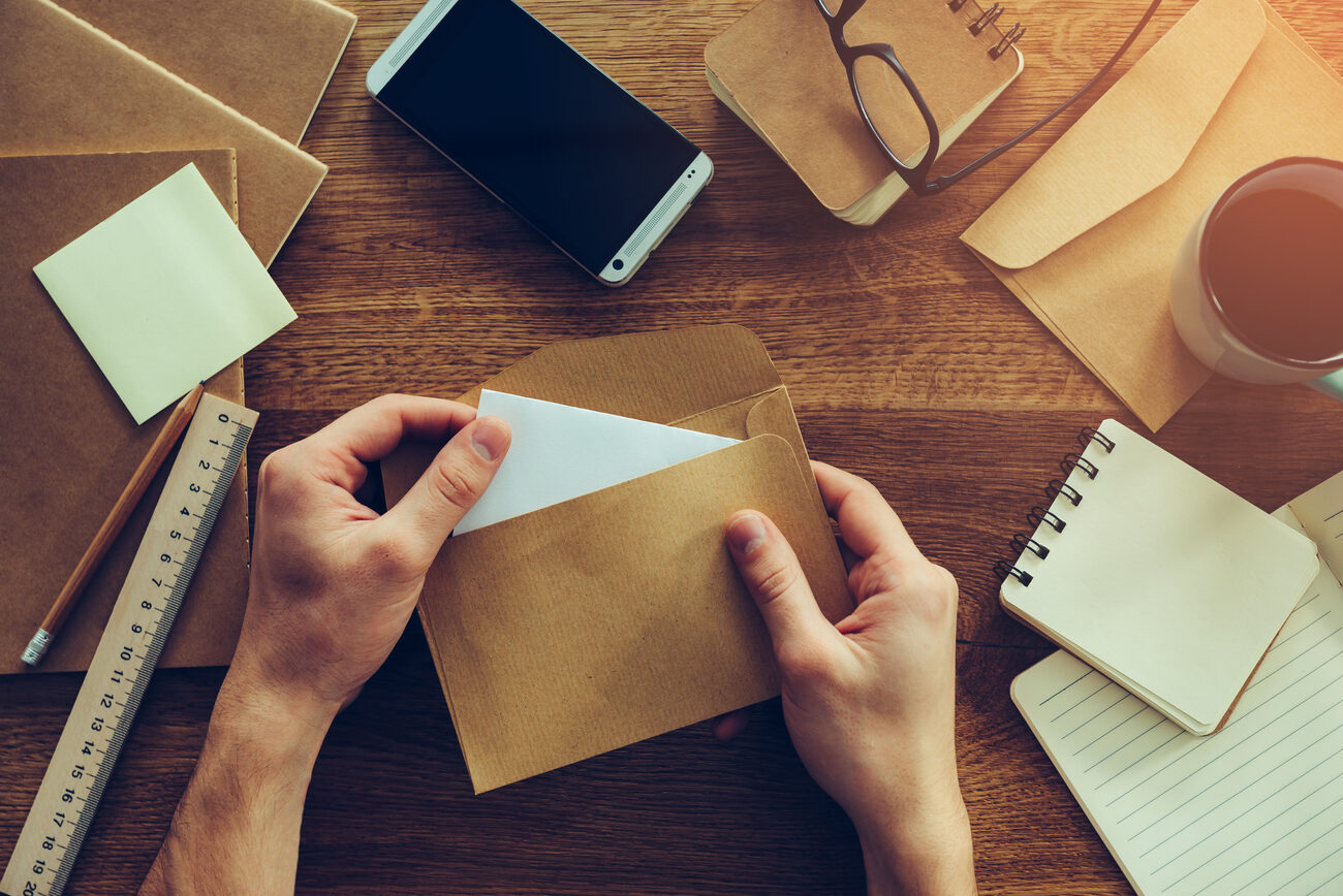 Hands putting paper into an envelope