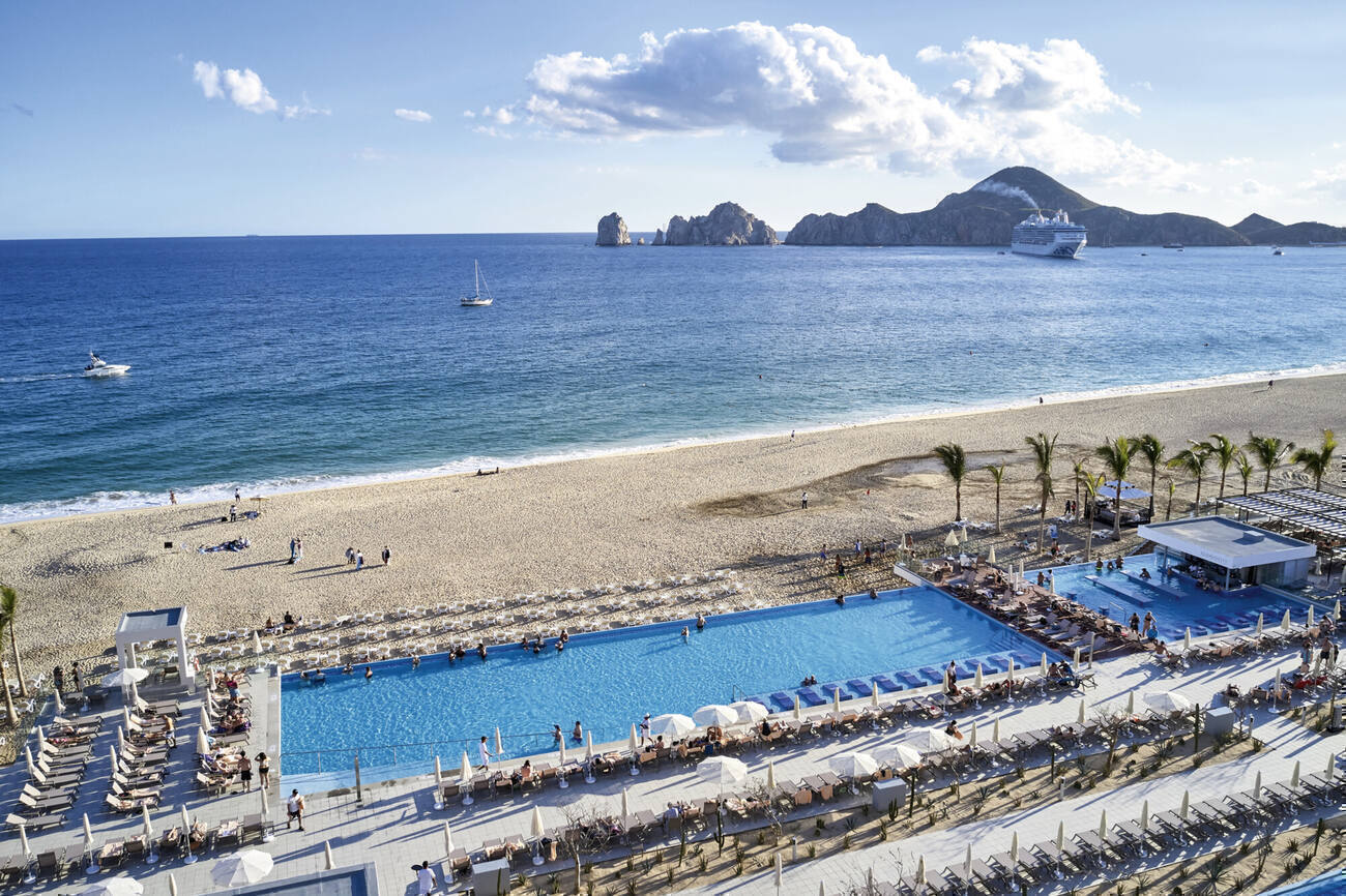 View of pools next to the beach with people walking around