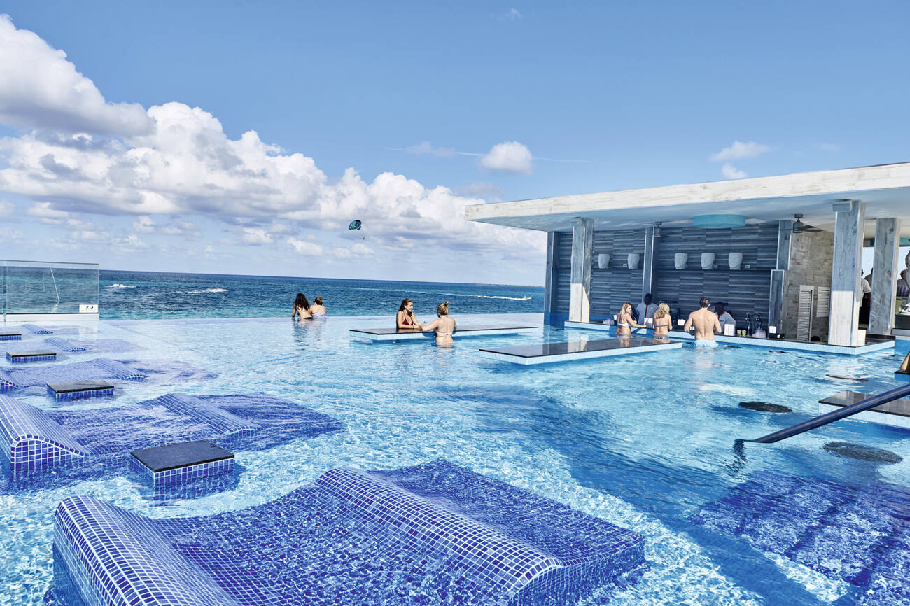 People lounging in an infinity pool with a swim up bar