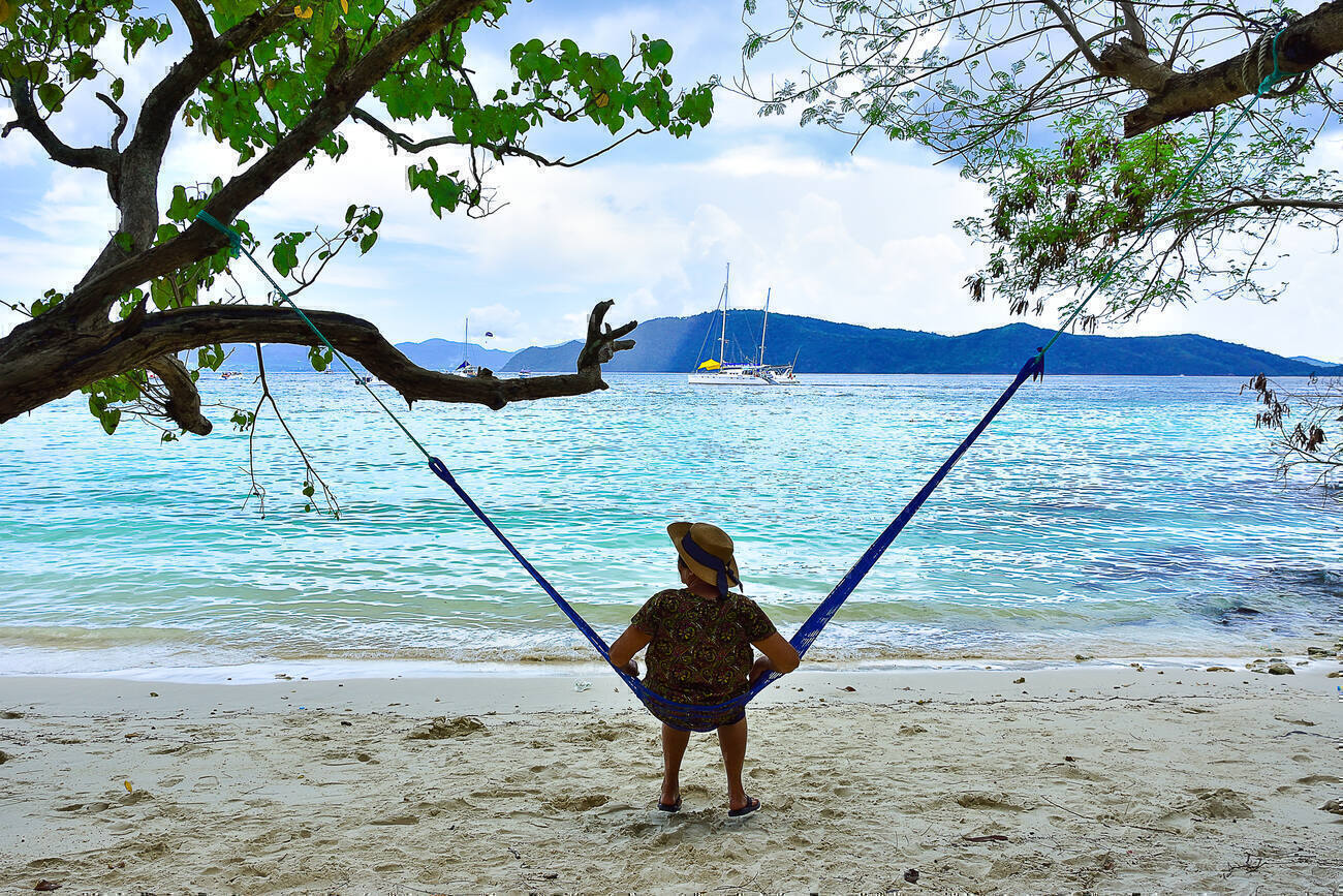 Person on a hammock overlooking the ocean with sailboats