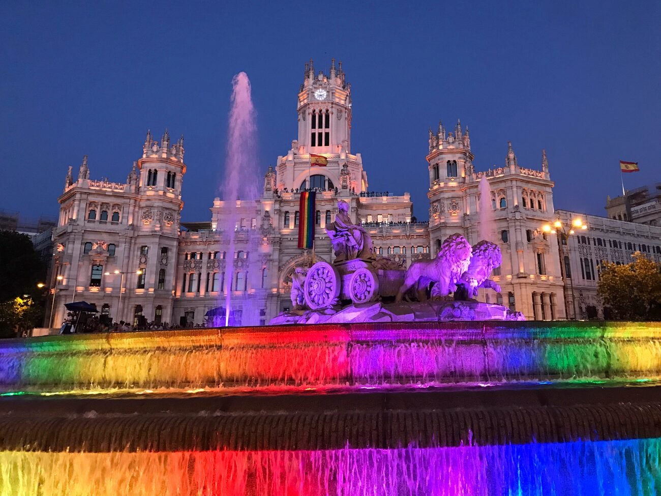 Building celebrating pride with a flag and fountain lit up