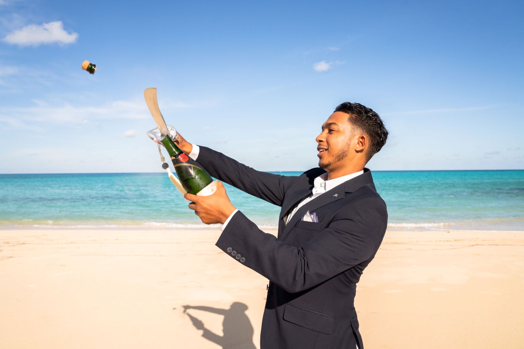 Man opening champagne bottle with a sword