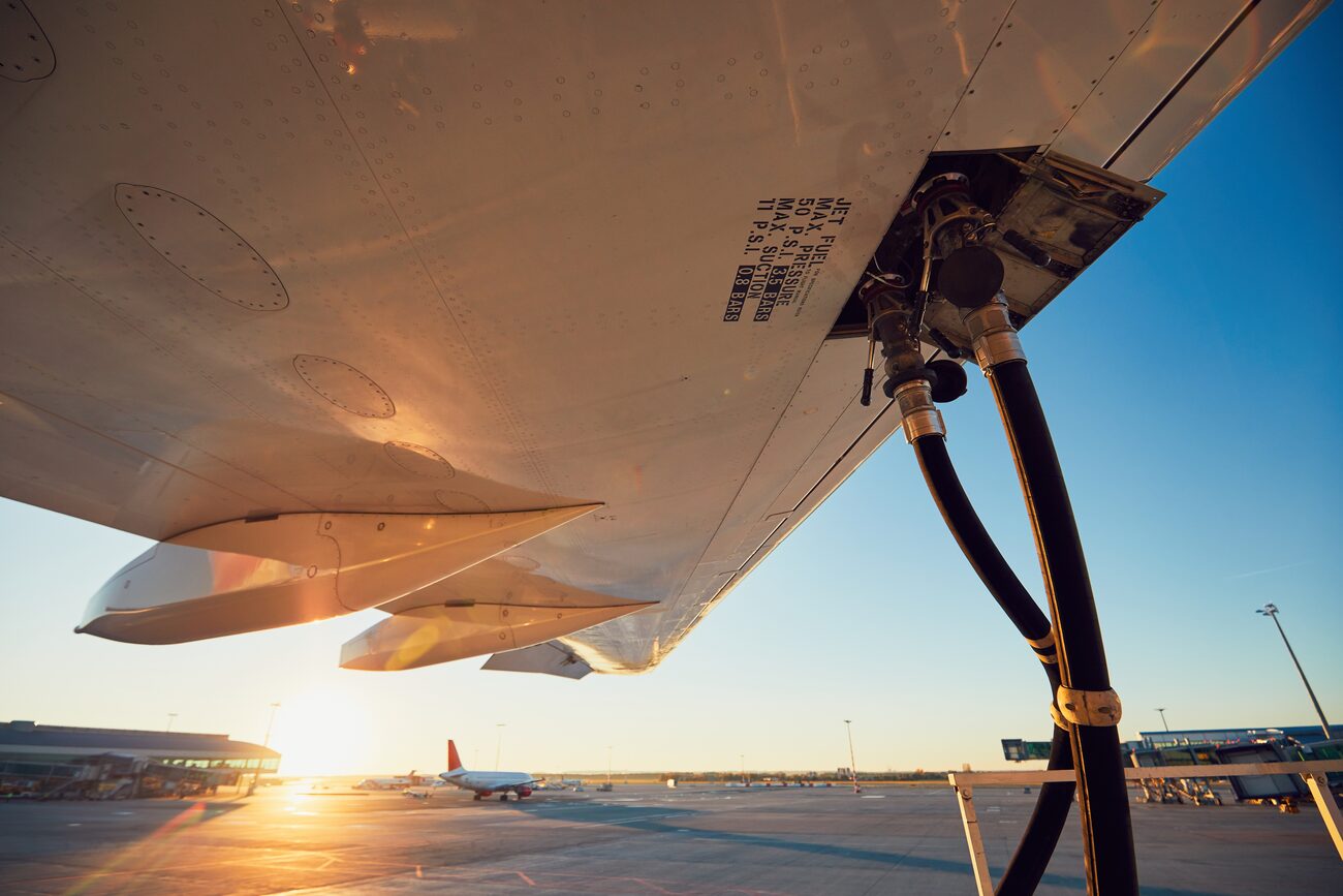 Airplane getting gas at airport during sunset