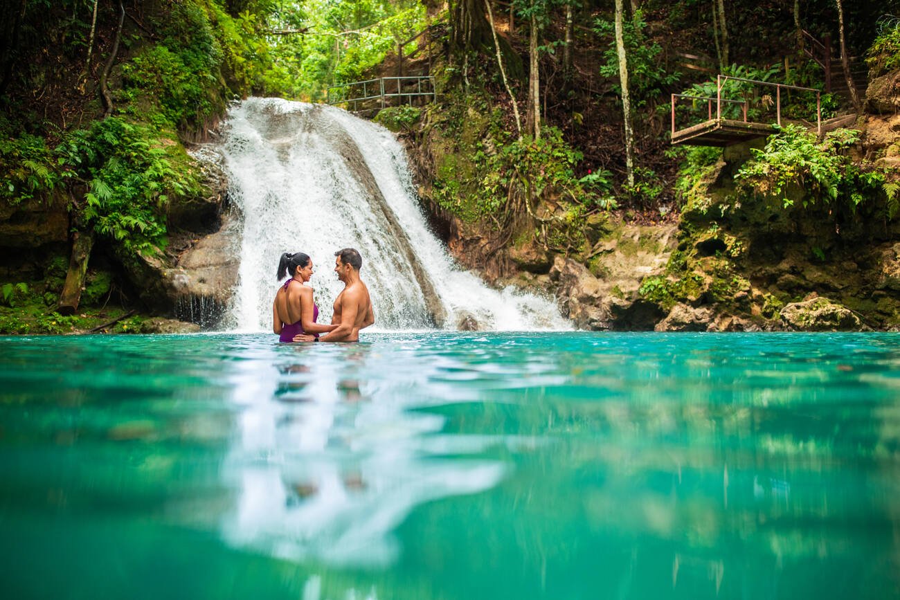 Couple in the water by a waterfall.