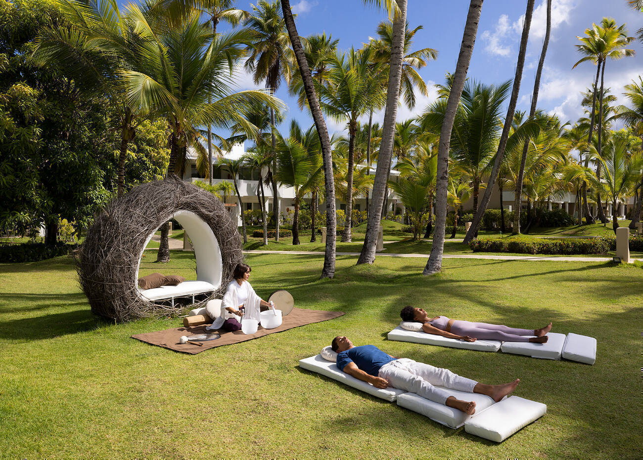 Group laying outside doing meditation with a woman using sound bowls