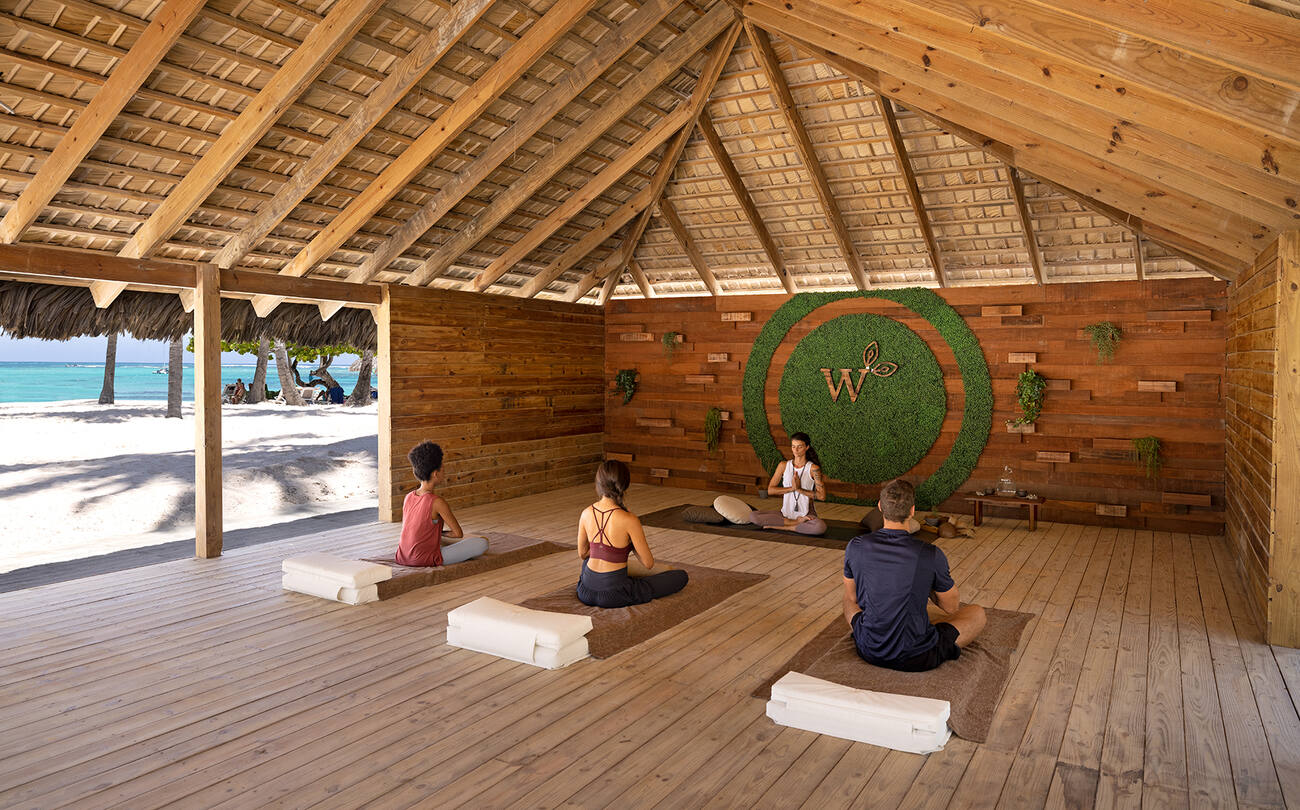 Group doing yoga from a yoga teacher with a view of the beach