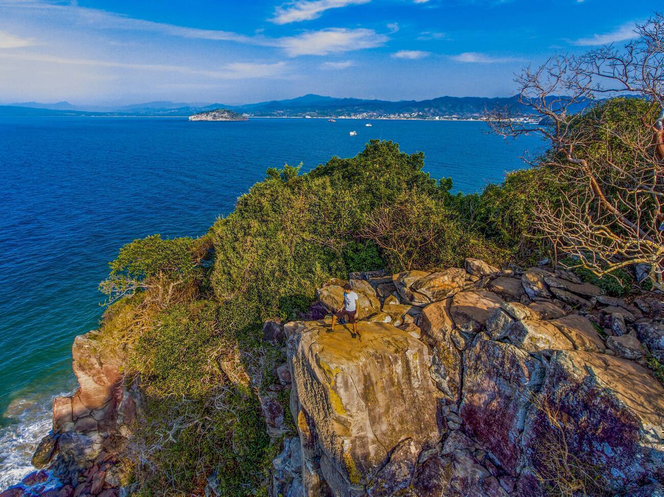 Man standing on a cliff with a view of the ocean